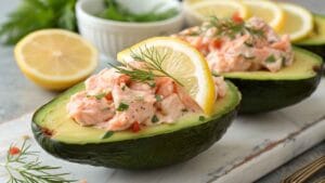 Salmon-Stuffed Avocados garnished with fresh herbs and lemon.