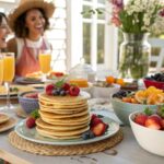 Brunch table with pancakes, fruit, and mimosas surrounded by happy friends.